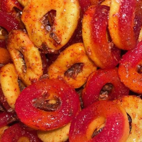Close up of Li Hing Mui Peach Rings, which are glazed and red in color, possibly with a sweet and tangy flavor profile.